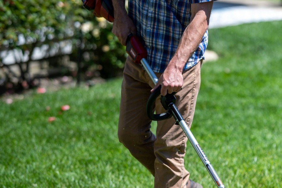 A man using a lawn mower to cut grass